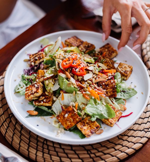 Woman having colorful healthy vegan vegetarian meal salad in summer cafe